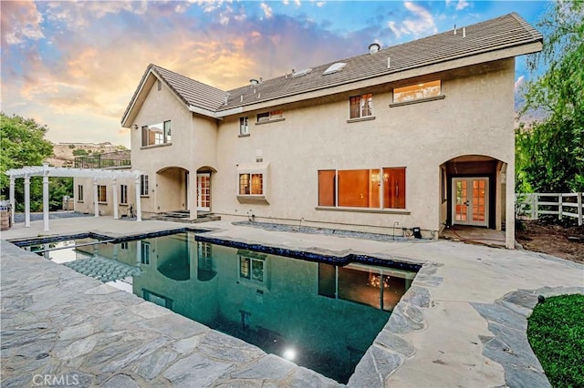 back house at dusk featuring french doors, a patio, and a pergola