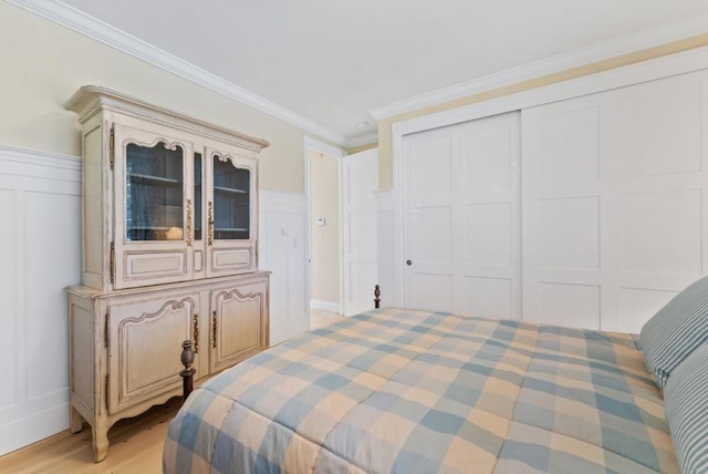 bedroom with light hardwood / wood-style flooring, ornamental molding, and a closet