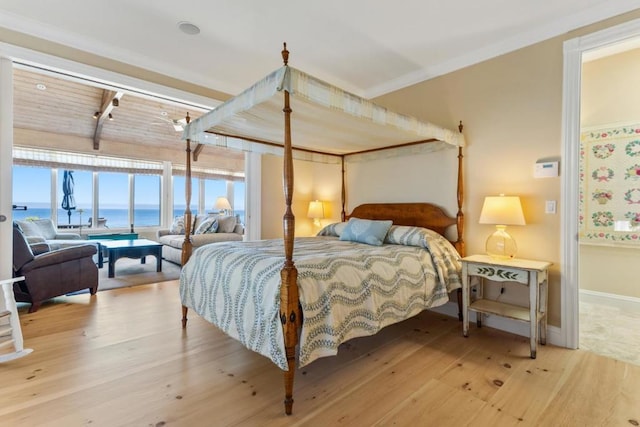 bedroom with hardwood / wood-style flooring, crown molding, and a water view