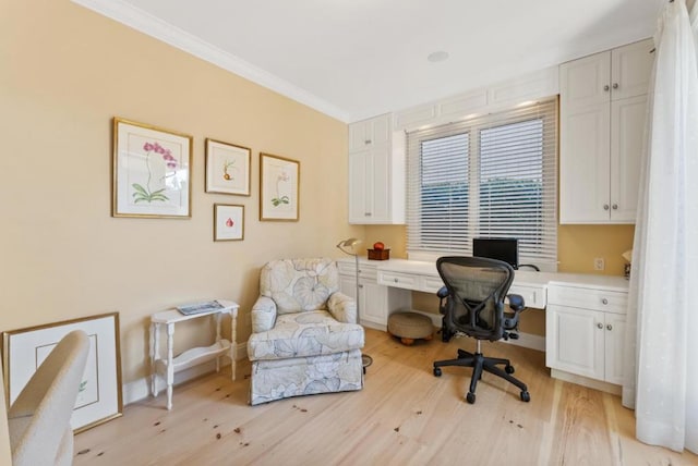 office space with ornamental molding, built in desk, and light hardwood / wood-style flooring