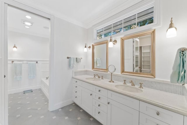 bathroom featuring vanity, crown molding, and a tub