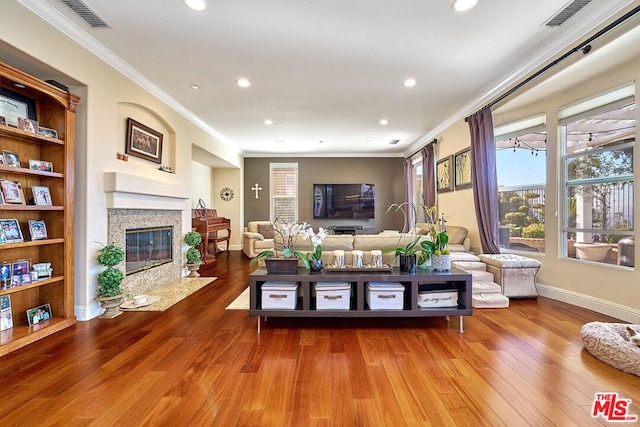 living room with wood-type flooring, a high end fireplace, and ornamental molding