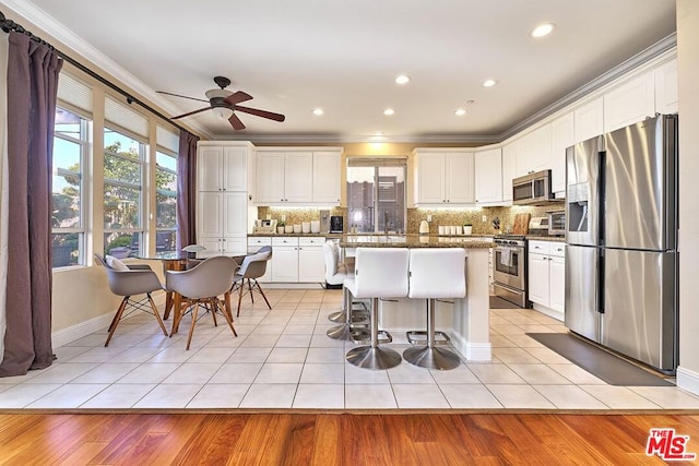 kitchen featuring white cabinets, a healthy amount of sunlight, stainless steel appliances, and a center island