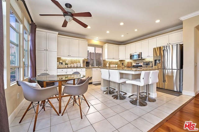 kitchen featuring white cabinets, a center island, stainless steel appliances, and light tile patterned flooring