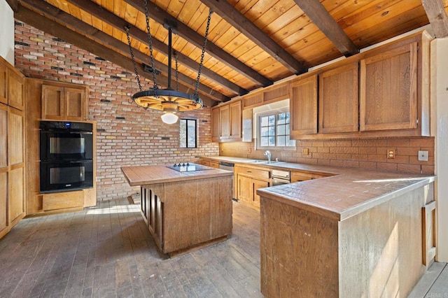 kitchen featuring tile countertops, a center island, black appliances, and wood-type flooring