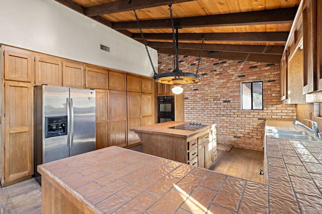 kitchen with sink, tile countertops, black appliances, and beamed ceiling