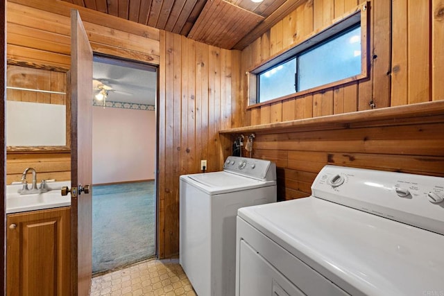 laundry room featuring sink, wooden walls, wooden ceiling, ceiling fan, and washer and clothes dryer