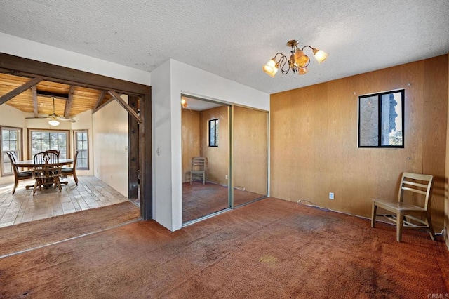 interior space featuring a textured ceiling, wooden walls, wood ceiling, carpet floors, and ceiling fan with notable chandelier