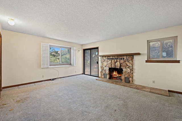 unfurnished living room with a textured ceiling, a stone fireplace, and carpet floors