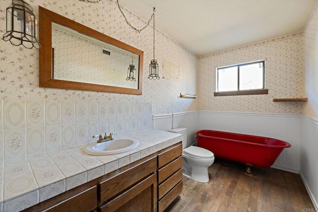 bathroom with toilet, vanity, a bath, and hardwood / wood-style floors