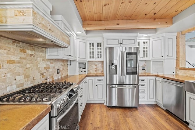 kitchen featuring appliances with stainless steel finishes, white cabinetry, backsplash, wooden ceiling, and custom range hood