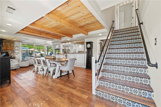 dining area featuring wooden ceiling, a wood stove, hardwood / wood-style floors, and beamed ceiling