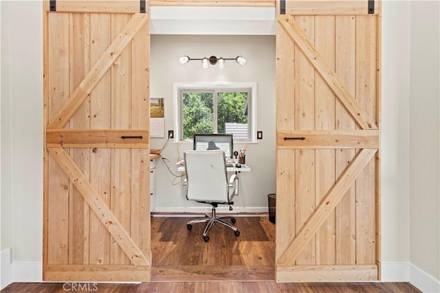 office featuring wood-type flooring and a barn door