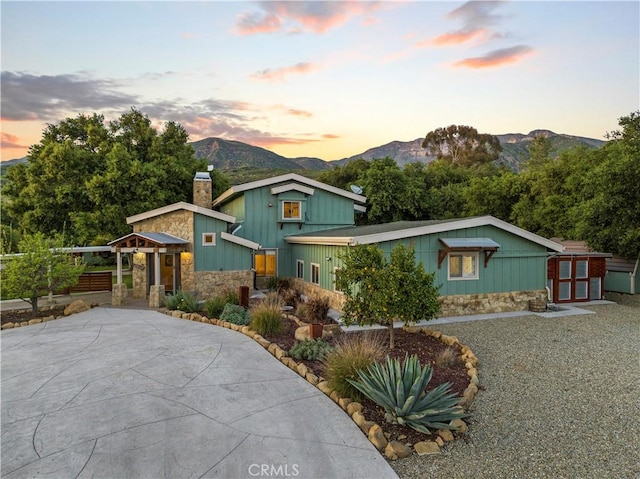 view of front of property featuring a mountain view and a storage shed