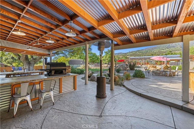 view of patio featuring a grill, an outdoor kitchen, and a mountain view