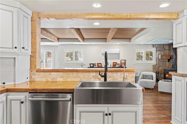 kitchen featuring dishwasher, sink, beamed ceiling, white cabinetry, and hardwood / wood-style flooring