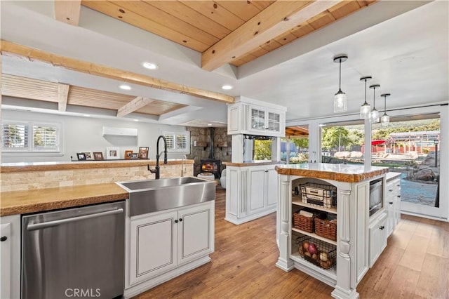 kitchen with pendant lighting, white cabinets, dishwasher, a kitchen island, and beamed ceiling