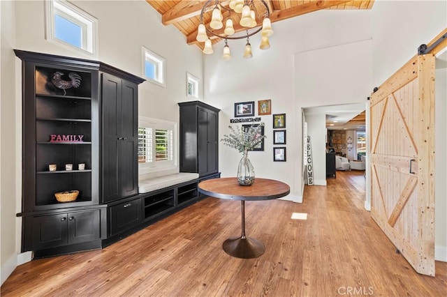 mudroom with wooden ceiling, wood-type flooring, beam ceiling, and a barn door