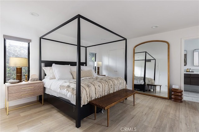 bedroom featuring ensuite bathroom and light wood-type flooring