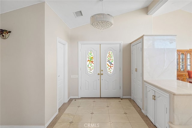 foyer featuring an inviting chandelier, light tile patterned floors, lofted ceiling, and french doors