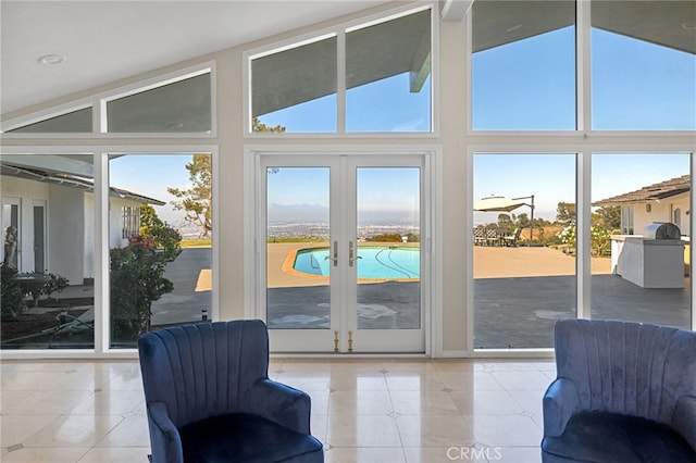 entryway with high vaulted ceiling, light tile patterned floors, french doors, and a wealth of natural light