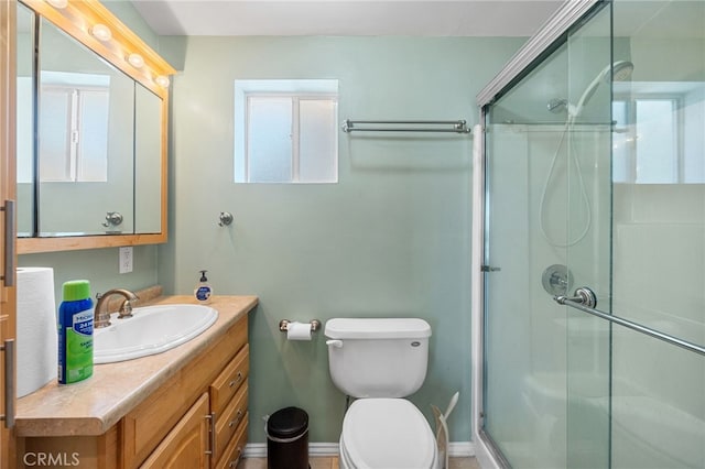 bathroom featuring toilet, a shower with shower door, and vanity