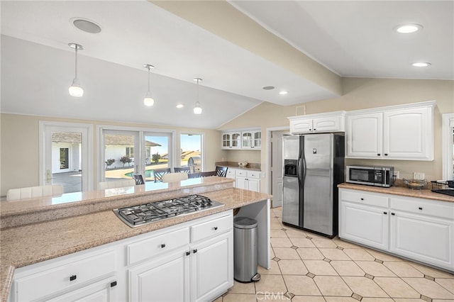 kitchen with appliances with stainless steel finishes, lofted ceiling, white cabinets, and hanging light fixtures