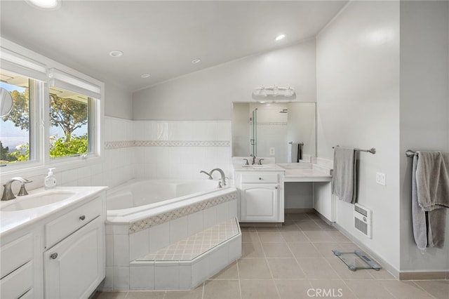 bathroom featuring tile patterned flooring, lofted ceiling, a relaxing tiled tub, and vanity