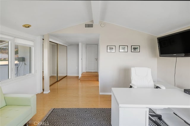 home office featuring light hardwood / wood-style flooring and lofted ceiling with beams