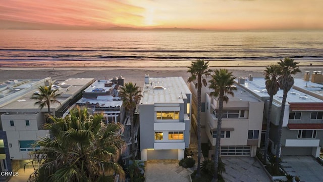 aerial view at dusk with a view of the beach and a water view