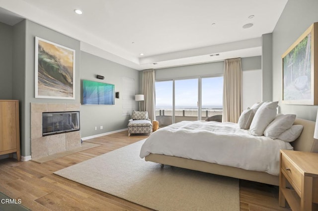 bedroom with light hardwood / wood-style flooring and a tiled fireplace