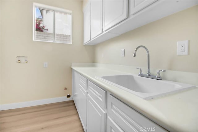 washroom with washer hookup, cabinets, light hardwood / wood-style flooring, and sink