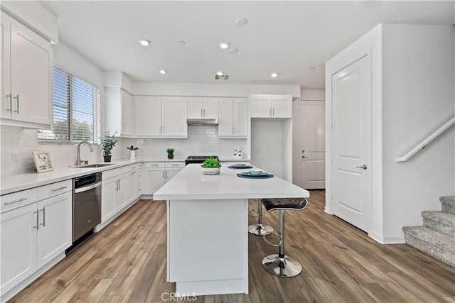 kitchen with a kitchen island, dishwasher, white cabinetry, and sink