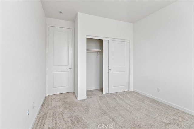 unfurnished bedroom with a closet and light carpet