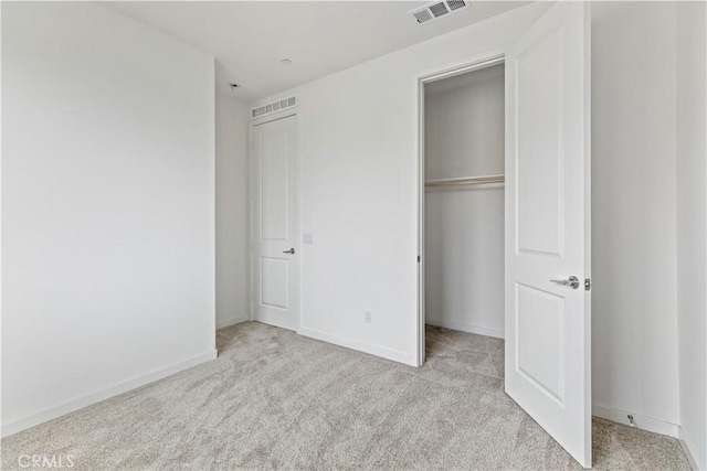 unfurnished bedroom featuring light colored carpet and a closet