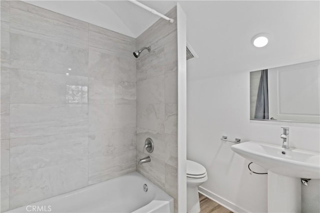 bathroom featuring toilet, tiled shower / bath, and hardwood / wood-style flooring