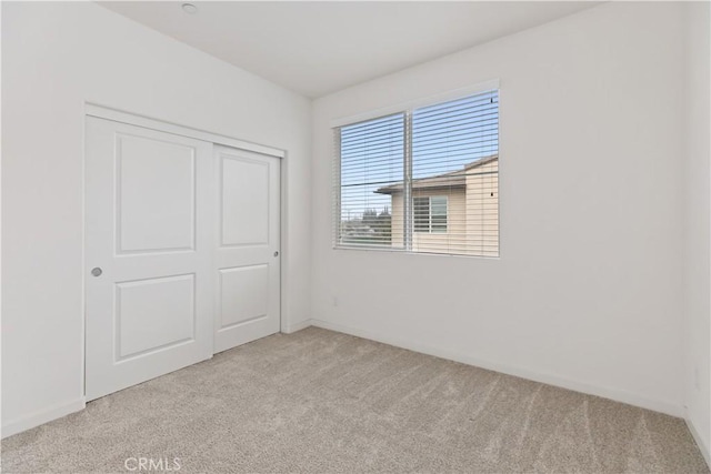 unfurnished bedroom with light carpet and a closet