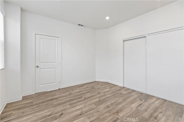 unfurnished bedroom featuring a closet and light hardwood / wood-style floors