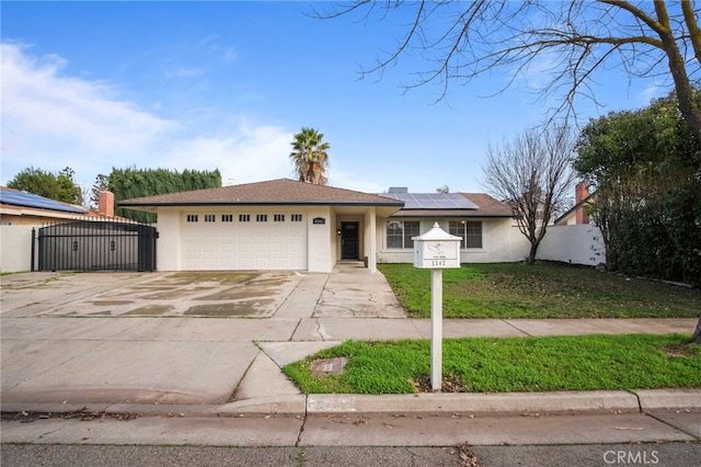 ranch-style home featuring a front yard, solar panels, and a garage