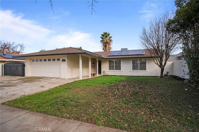 ranch-style house featuring a front lawn, solar panels, and a garage