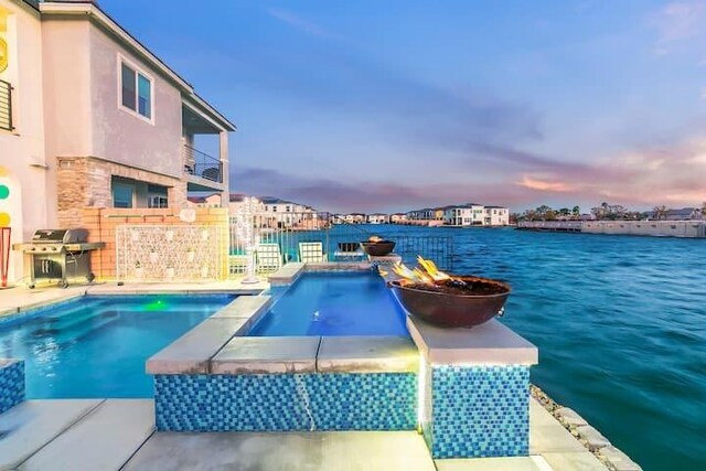 pool at dusk featuring a grill and a water view