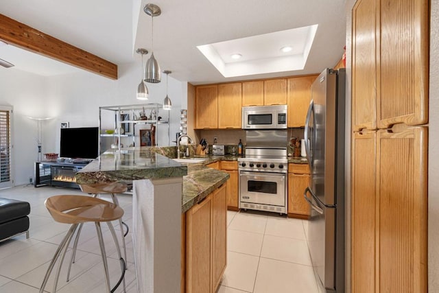 kitchen featuring pendant lighting, sink, a tray ceiling, stainless steel appliances, and light tile patterned floors