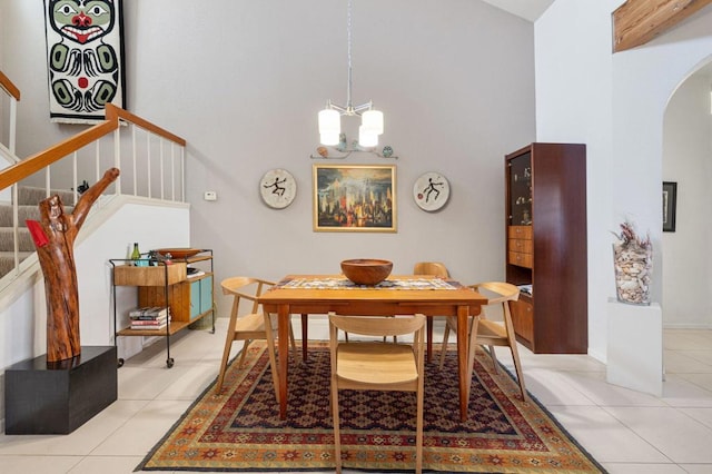 dining space featuring a high ceiling, light tile patterned floors, and a notable chandelier