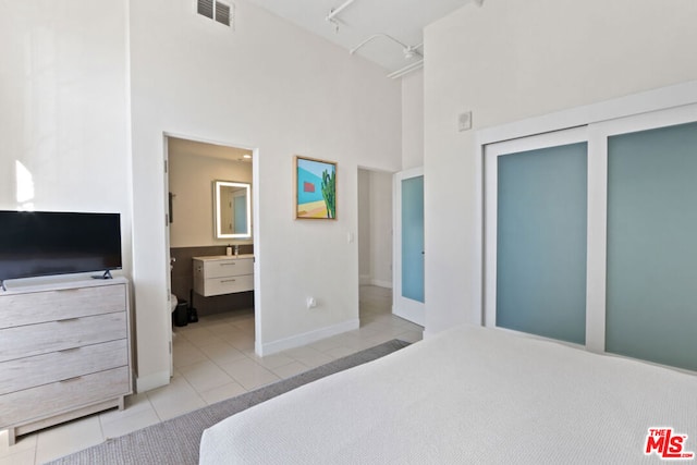 tiled bedroom featuring a high ceiling, sink, and ensuite bath