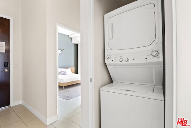 laundry area featuring stacked washer and clothes dryer and light tile patterned flooring