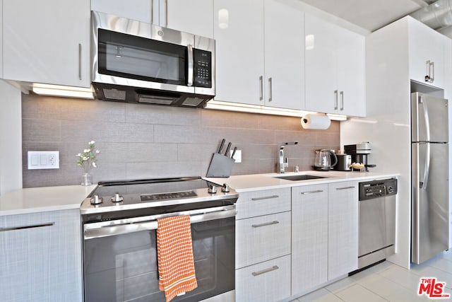 kitchen with light tile patterned floors, white cabinetry, stainless steel appliances, backsplash, and sink