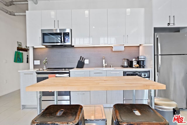 kitchen with tasteful backsplash, sink, stainless steel appliances, and white cabinetry