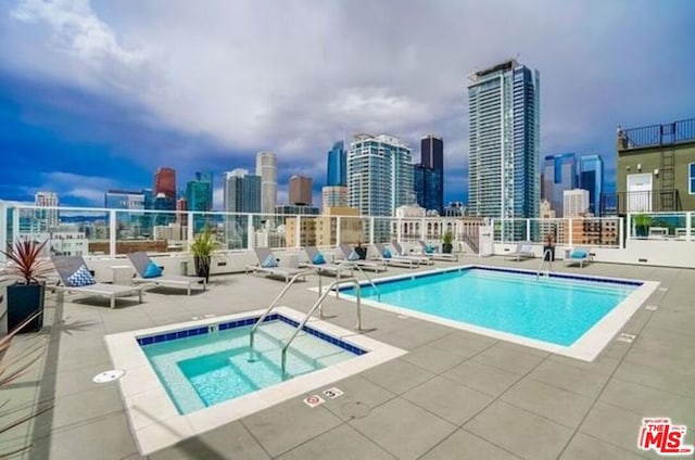 view of swimming pool featuring a hot tub and a patio