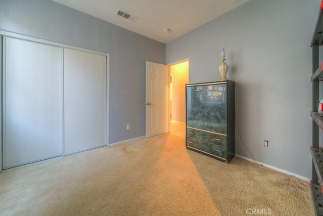 unfurnished bedroom with light carpet and a closet