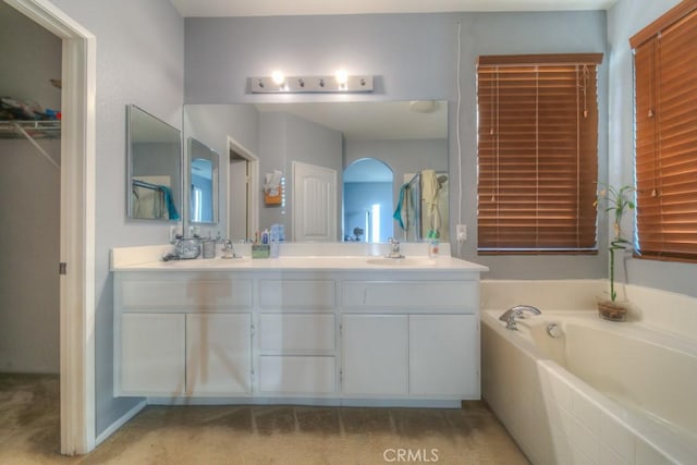 bathroom featuring tiled tub and vanity